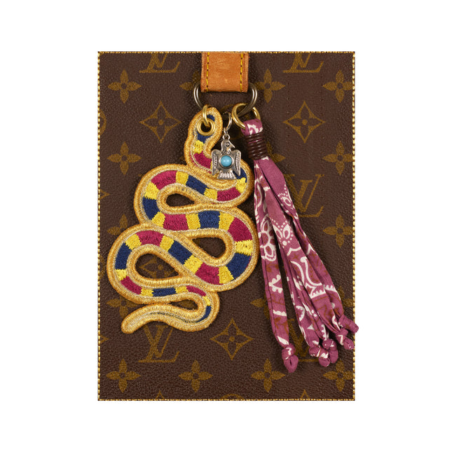 Decorative keychain with snake design on a Louis Vuitton patterned background
