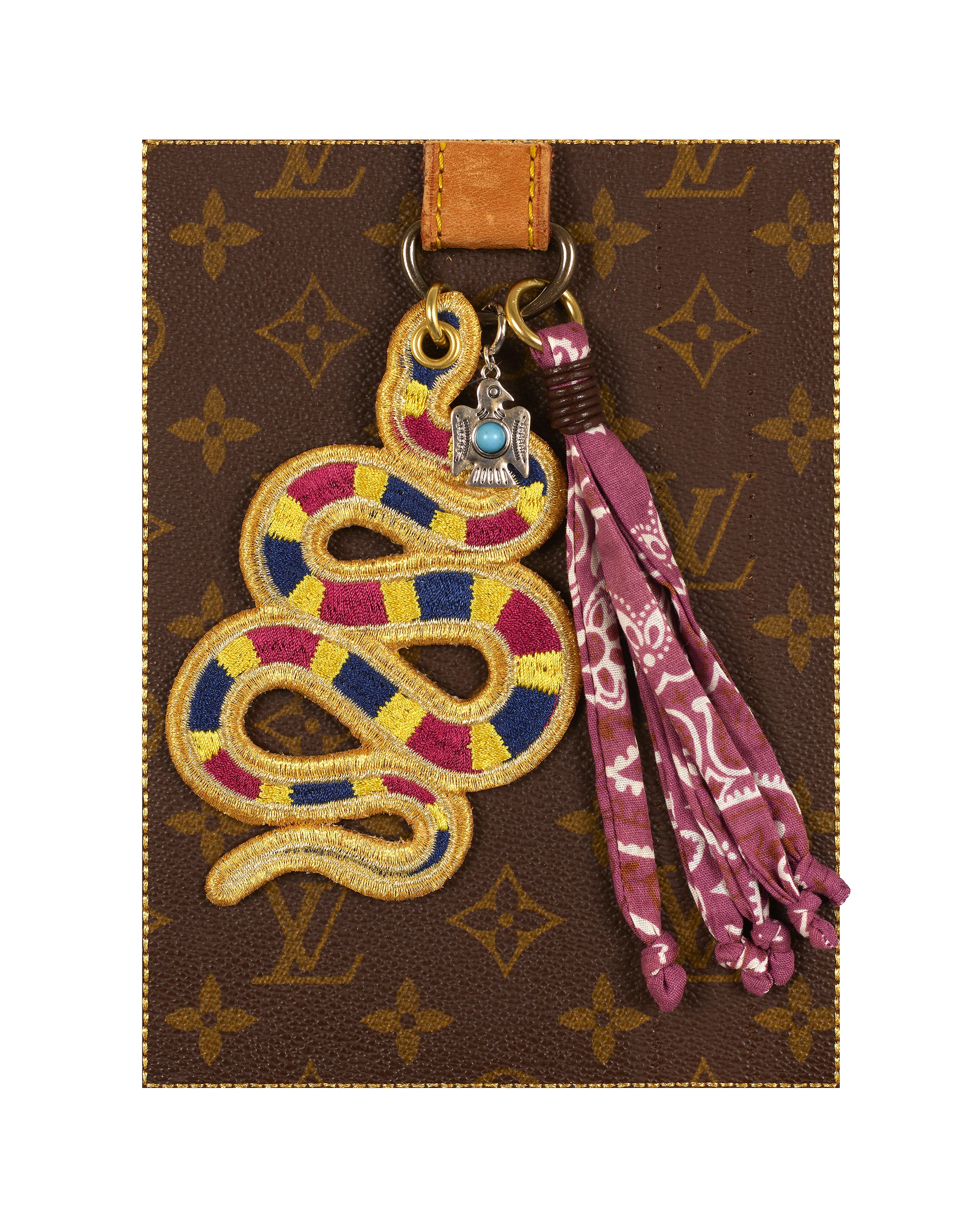 Decorative keychain with snake design on a Louis Vuitton patterned background